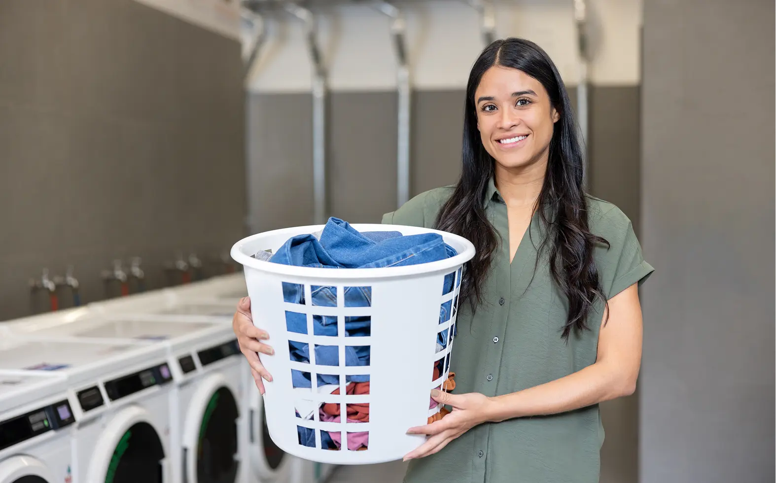 Woman holding laundry basket in laundromat